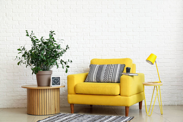 Sisätilojen olohuone keltainen nojatuoli, pöytävalaisin ja huonekasvi - Valokuva, kuva
