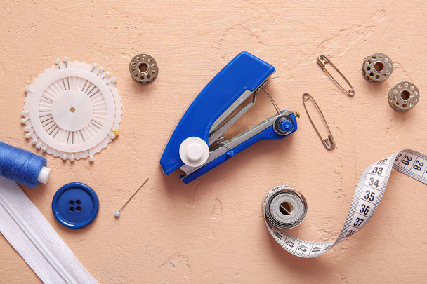 Máquina de coser manual con diferentes suministros sobre fondo beige - Foto, Imagen