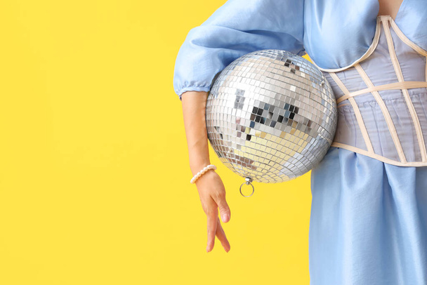 Модна молода жінка з диско-кулькою на жовтому фоні - Фото, зображення