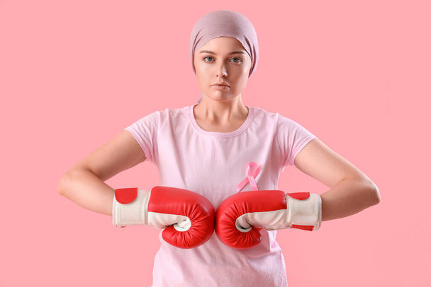 Young woman after chemotherapy with pink ribbon on color background. Breast cancer awareness concept - Photo, Image