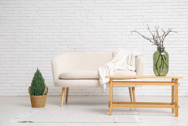 Sofá blanco y jarrón con ramas de árbol en la mesa de centro en la elegante sala de estar - Foto, Imagen