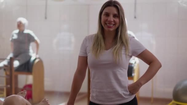 Pilatesin muotokuva Nainen Ohjaaja seisoo urheiluateljeessa, paikalliset yrityspalveluihmiset - Materiaali, video