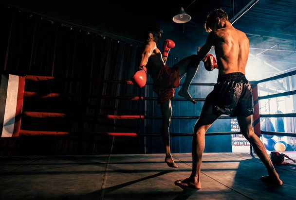 Азиатский и кавказский боксер Муай Тай развязывает атаку на колено в упорной тренировке по боксу, нанося удар коленом спарринг-тренеру, демонстрируя технику и мастерство Муай Тая по боксу. Импет - Фото, изображение