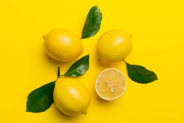 Many fresh ripe lemons with green leaves on colored background, top view, space for text. - Photo, Image