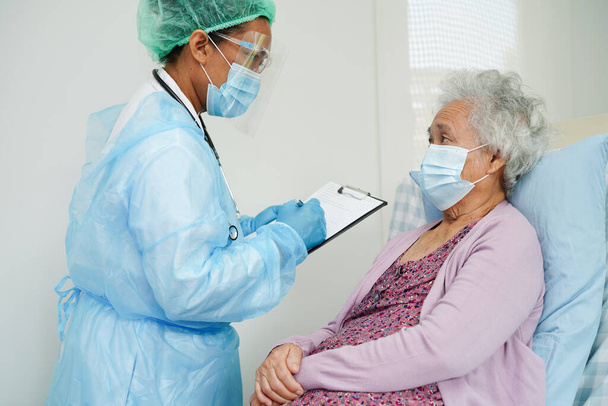 医師チェックアジアの年上の女性患者を保護するためのマスクを身に着けていますcovid coronavirus. - 写真・画像