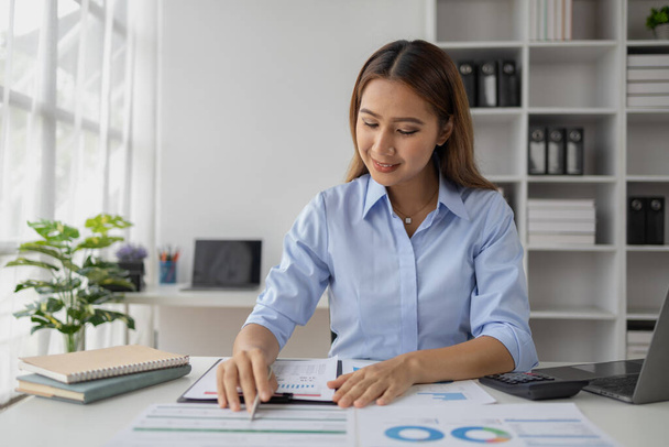 Asian woman working in startup company office, businesswoman checking documents and company performance report to analyze and find ways to grow company. Business administration concept. - Photo, Image