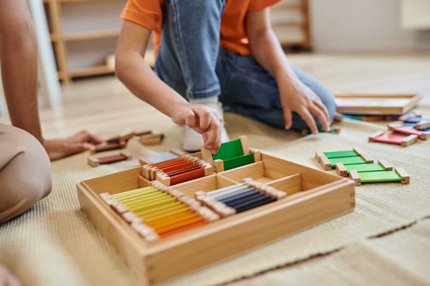 Montessori concetto di scuola, vista ritagliata di ragazza che gioca gioco di corrispondenza dei colori vicino insegnante, gioco basato - Foto, immagini