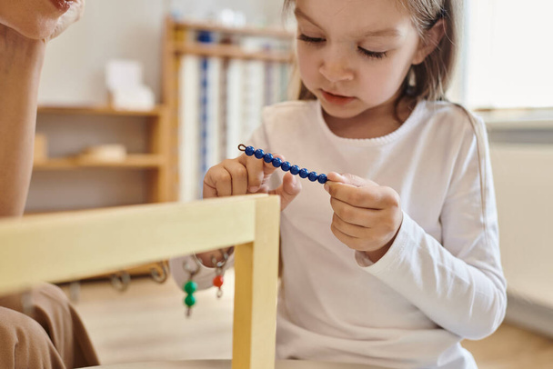 montessori concept, girl playing with color bead stairs near teacher, cavalletto in legno, ravvicinato - Foto, immagini