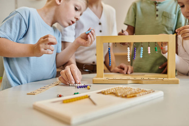 montessori školní koncept, multikulturní děti hrající si s barevnými perličkovými schody v blízkosti učitele - Fotografie, Obrázek