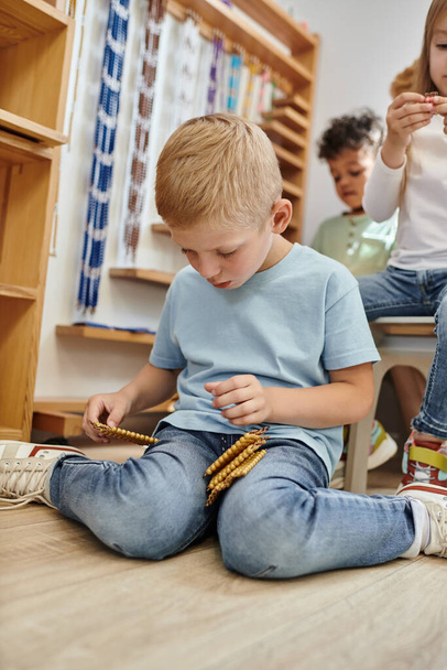 ξανθό αγόρι που κρατά Montessori χάντρες υλικό, καταμέτρηση, μάθηση μέσα από το παιχνίδι, ποικίλα παιδιά - Φωτογραφία, εικόνα