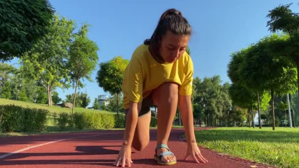 Multiraciální mladá žena začíná den osvěžujícím ranním běháním. Vyrazila s nízkým startem na běžeckou dráhu a rychle se pustila do běhu. Nízký úhel pohledu určený sportovci připraveni na cvičení - Záběry, video