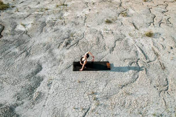 Kobieta uprawiająca jogę i stojąca na gwoździach na pustyni o zachodzie słońca.Koncepcja jogi i stania na paznokciach - Zdjęcie, obraz