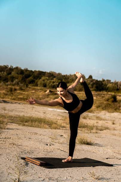 Frau macht Yoga und steht bei Sonnenuntergang auf Nägeln in der Wüste. - Foto, Bild