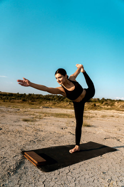 Женщина делает йогу и стоя на ногтях в пустыне на sunset.The концепции йоги и стоя на ногтях - Фото, изображение