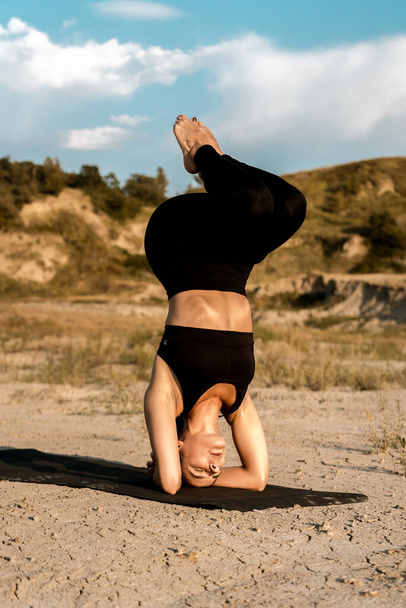 Жінка робить йогу і стоїть на цвяхах у пустелі на заході сонця. Концепція йоги і стояння на цвяхах - Фото, зображення