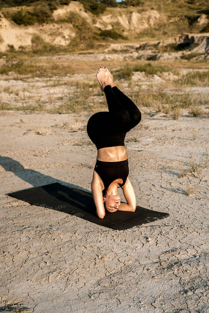 Gün batımında kadın yoga yapıyor ve çölde çivilerin üzerinde duruyor. Yoga ve çivilerin üzerinde durmak kavramı. - Fotoğraf, Görsel