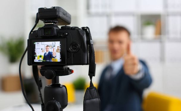Male in suit and tie show confirm sign arm making promo videoblog or photo session in office camcorder to tripod closeup. Vlogger promotion selfie solution or finance advisor management information - Photo, Image