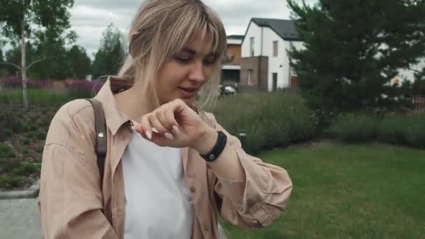 Dolly colpo di giovane donna caucasica ricodifica messaggio vocale su smart watch mentre si cammina con il bambino nel passeggino - Filmati, video