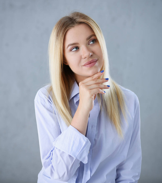 Portrait of a sexy woman in a mans shirt wearing on a gray background looks at the camera. Smiling look advice to give wants objections are not accepted. - Photo, Image