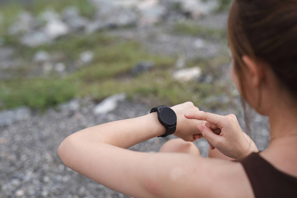 Young woman jogging and looking at his smart watch in the evening at the park.. - Photo, Image