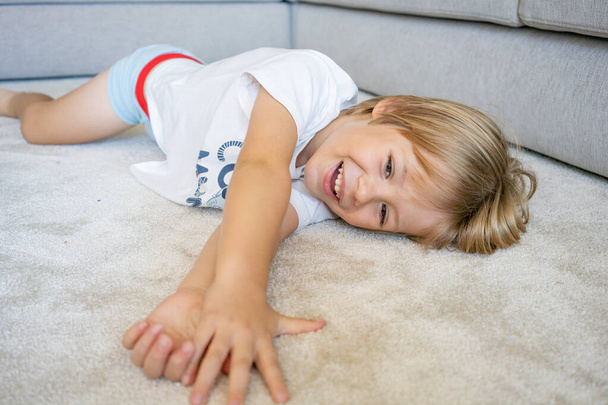 portrait of a little boy smiling lying on a carpet at home - Photo, Image