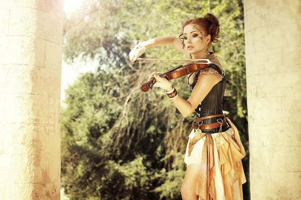 Redhair piękna kobieta z tatuazy na jej twarz, grając na vio - Zdjęcie, obraz