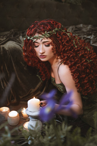 fata capelli rossi donna con candele, fiori e piante, fantasia scura principessa druida - Foto, immagini