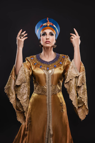 primer plano retrato de estudio de una hermosa mujer con ojos marrones y maquillaje de noche en la imagen de la reina Cleopatra, corona, collar - Foto, Imagen