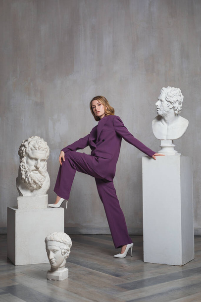 joven hermosa mujer rubia con una escultura, retrato de estudio de moda, mujer en un traje  - Foto, imagen