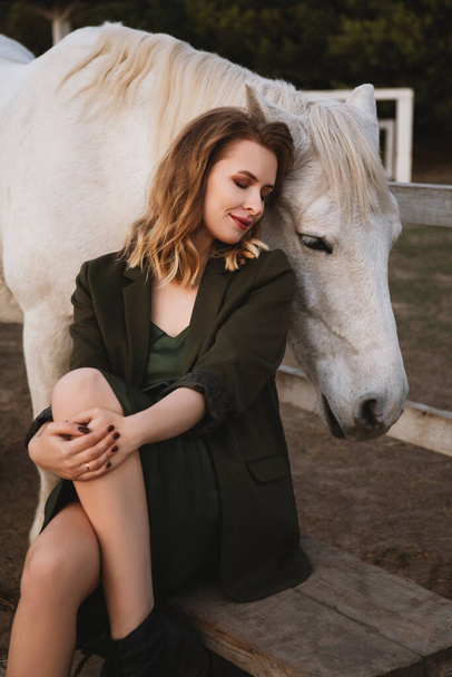 kaunis nainen istuu lähellä aitaa hevosten kanssa - Valokuva, kuva