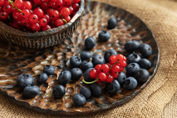 Teller mit saisonalen Beeren auf dem Tisch, auf grobem Tuch, gesundes Frühstück, Sommerernte - Foto, Bild