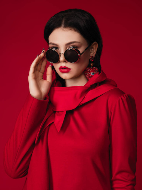 Загальна модель червоної моди в пальто та шарфі голови. Студійна фотографія брендового одягу. Брюнетка жінка в повсякденному вбранні. - Фото, зображення