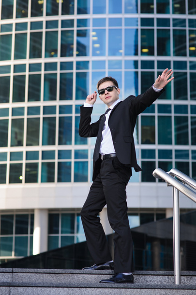 Hombre de negocios satisfecho agitando la mano, de pie en una escalera
. - Foto, imagen