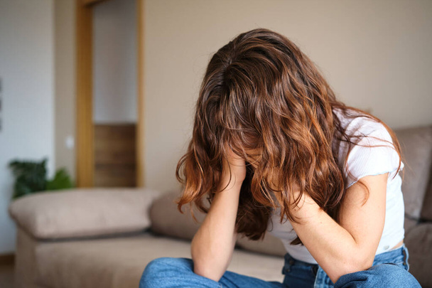 Smutná žena zakrývající obličej rukama sedícími doma na pohovce - Fotografie, Obrázek