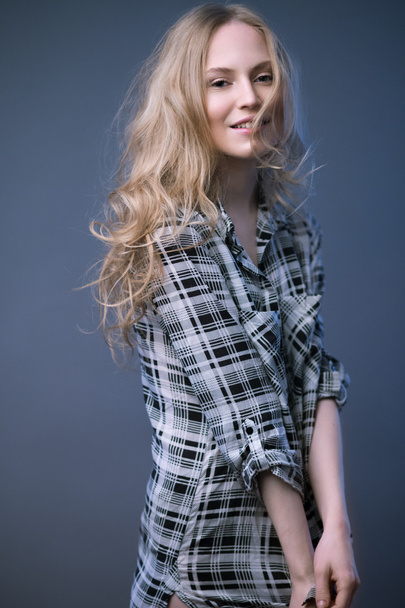 Beautiful blonde girl in a shirt with a light makeup and loose hair. Model tests. - Fotó, kép