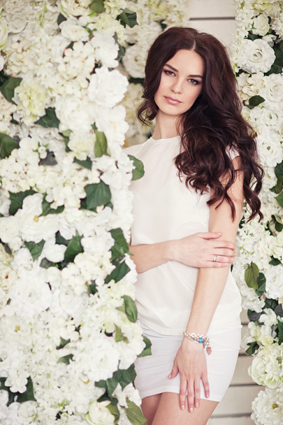 Joven chica hermosa cerca de flores blancas. Humor de primavera
. - Foto, Imagen