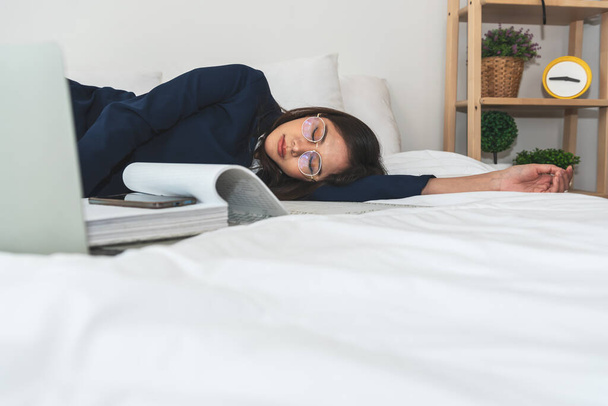 Azjatycka bizneswoman atrakcyjna i młoda, śpi na białym łóżku podczas pracy. do ciężkiej pracy nad koncepcją sukcesu pracy. - Zdjęcie, obraz