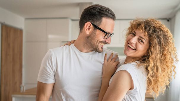 boldog kaukázusi felnőtt pár férfi és nő otthon együtt mosoly férj és feleség vagy barát és barátnő stand szórakozni - Fotó, kép