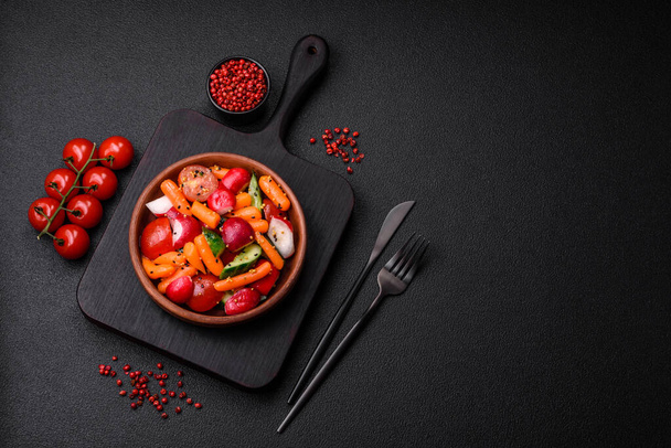 Λαχταριστή, φρέσκια, ζουμερή σαλάτα με ραπανάκια, ντομάτες, καρότα, αγγούρι, μπαχαρικά και βότανα σε σκούρο μπετόν φόντο - Φωτογραφία, εικόνα