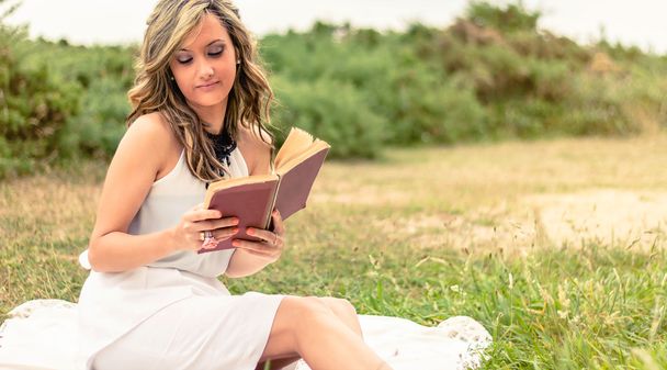 ロマンチックな女の子屋外に座って本を読んで - 写真・画像