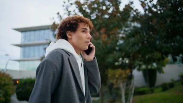 Sakin hipster açık havada akıllı telefon konuşuyor. Genç adam sonbahar caddesinde yürürken telefonla konuşuyor. Kendine güveni tam bir delikanlı konuşuyor. Sıradan gençler arkadaş toplantısına gidiyor. Kentsel yaşam tarzı konsepti  - Video, Çekim