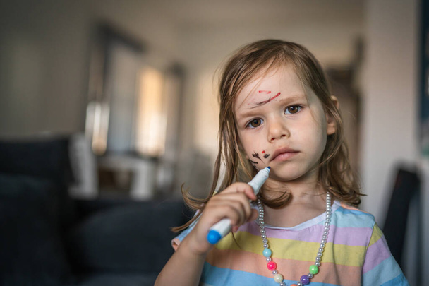 біла дівчинка малюк з розфарбованим кольором малює і плями на обличчі - Фото, зображення