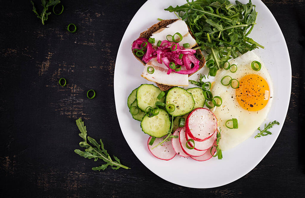 Kahvaltıda. Yağda yumurta, taze sebze salatası ve domuz yağlı sandviç. Keto diyeti. Üst görünüm - Fotoğraf, Görsel