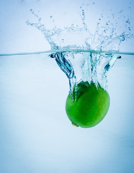 Fresh lime falling into water, on white - Foto, Imagem