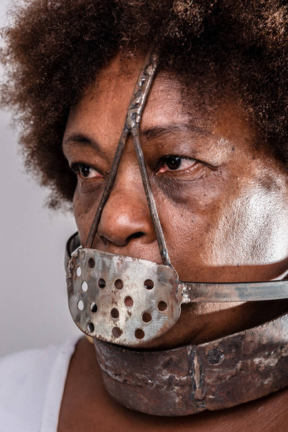 Portret czarnej kobiety w żelaznej masce niewolnictwa zakrywającej usta. Reprodukcja studia. - Zdjęcie, obraz
