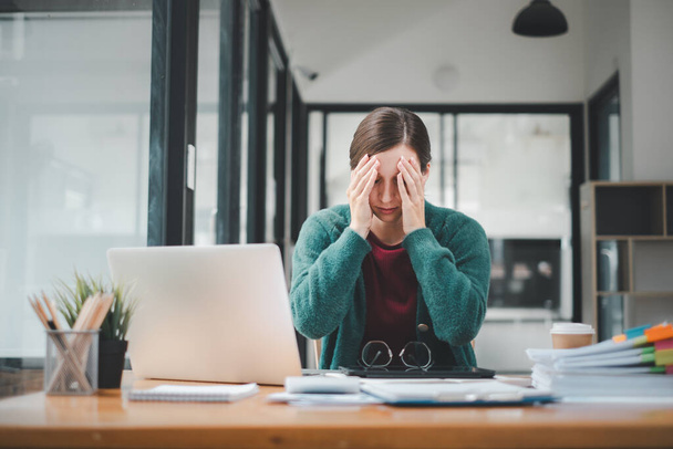 Уставшая деловая женщина хочет спать и скучно сидеть за столом в течение длительного времени и имеет офисный синдром - Фото, изображение