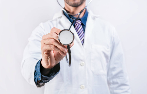 Κοντινό πλάνο του γιατρού που κρατάει το στηθοσκόπιο απομονωμένο. Μη αναγνωρίσιμος γιατρός που κρατά στηθοσκόπιο σε λευκό φόντο - Φωτογραφία, εικόνα