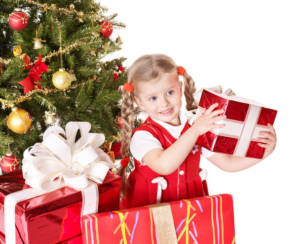 Child giving gift box by christmas tree. - Valokuva, kuva