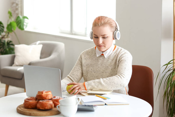 Female student in headphones studying with laptop at home - Photo, Image