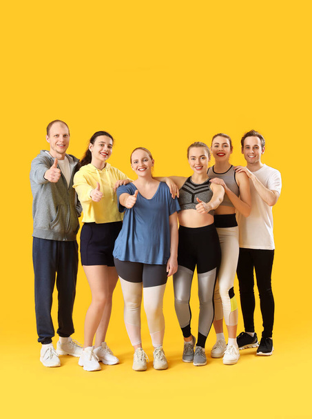 Groep sportieve jongeren met duimen omhoog op gele achtergrond - Foto, afbeelding